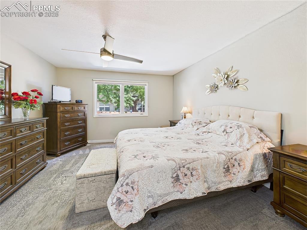 Primary Bedroom – Large picture window frames the landscaped view outside, flooding the room with natural light.