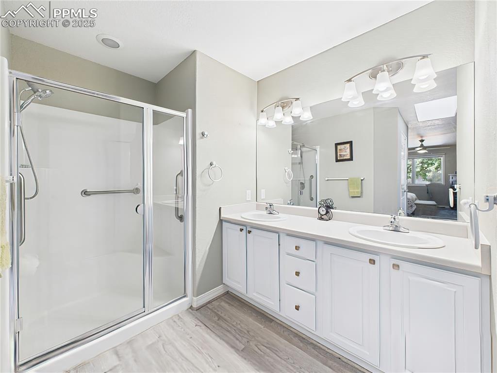 Primary Bathroom – Bright and spacious ensuite featuring a dual-sink vanity, large mirror, and a walk-in shower with glass doors and safety grab bars.