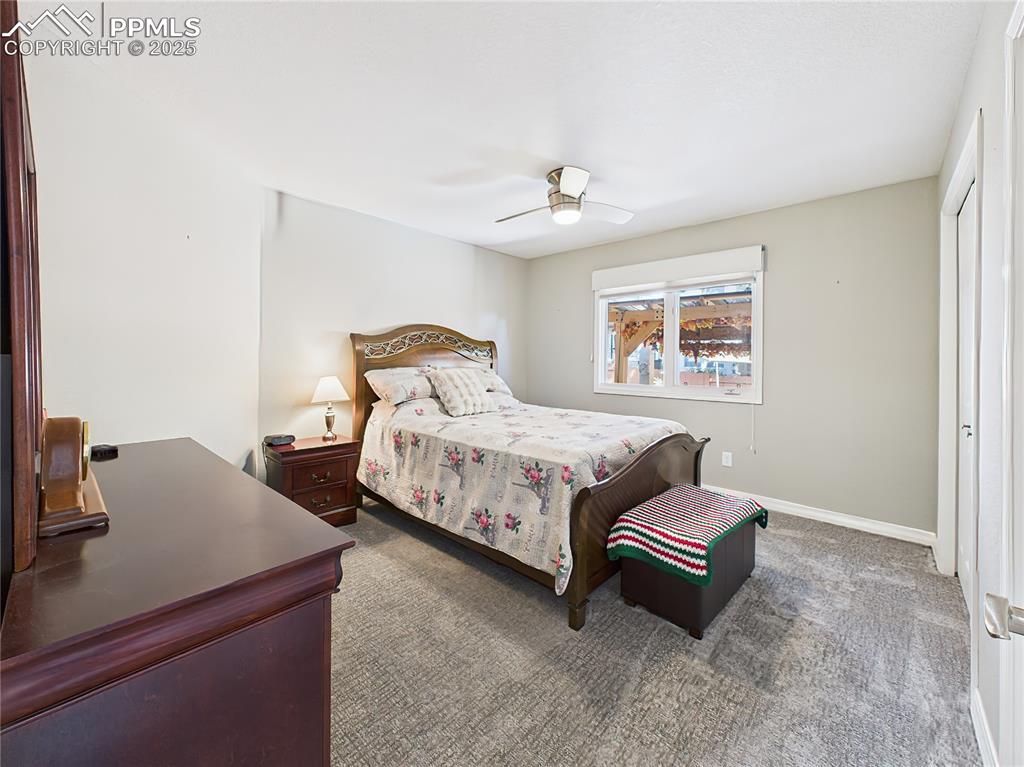 Second Bedroom – Secondary bedroom features a ceiling fan, plush carpet, and window overlooking the rear patio area.