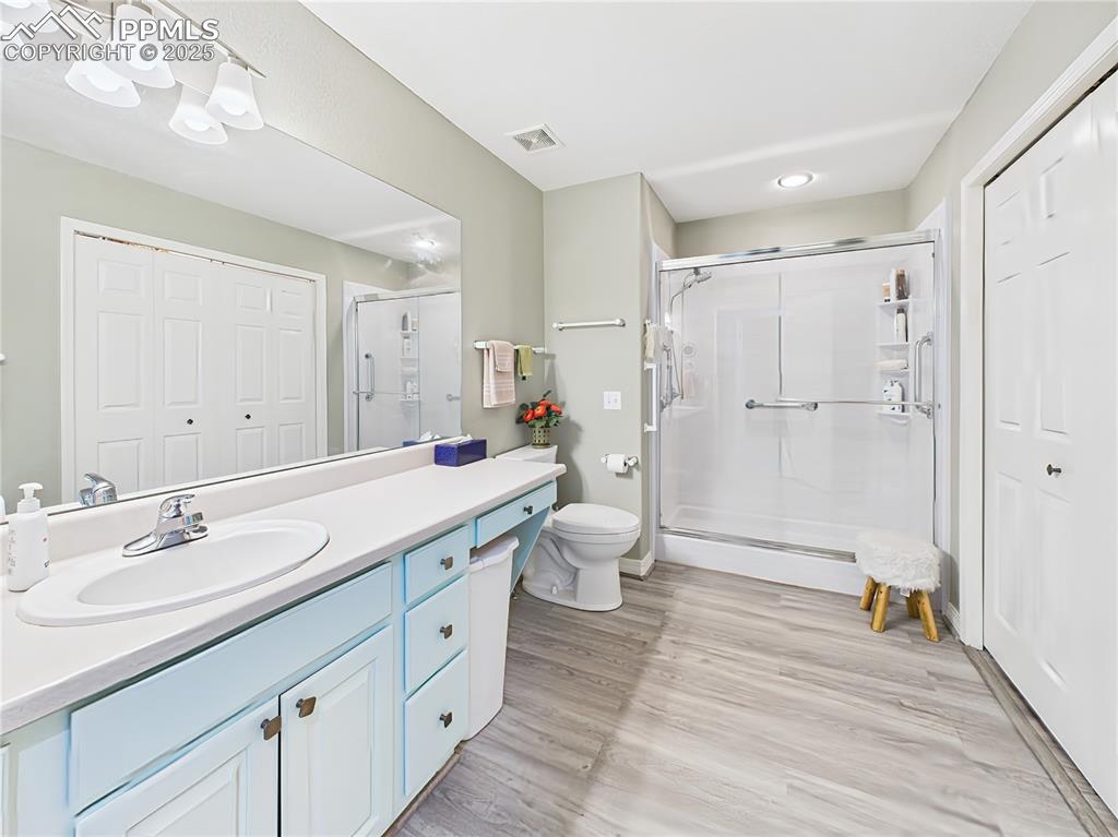 Guest Bathroom – Spacious guest bath with an extended vanity, full-width mirror, and walk-in shower featuring sliding glass doors and grab bars.
