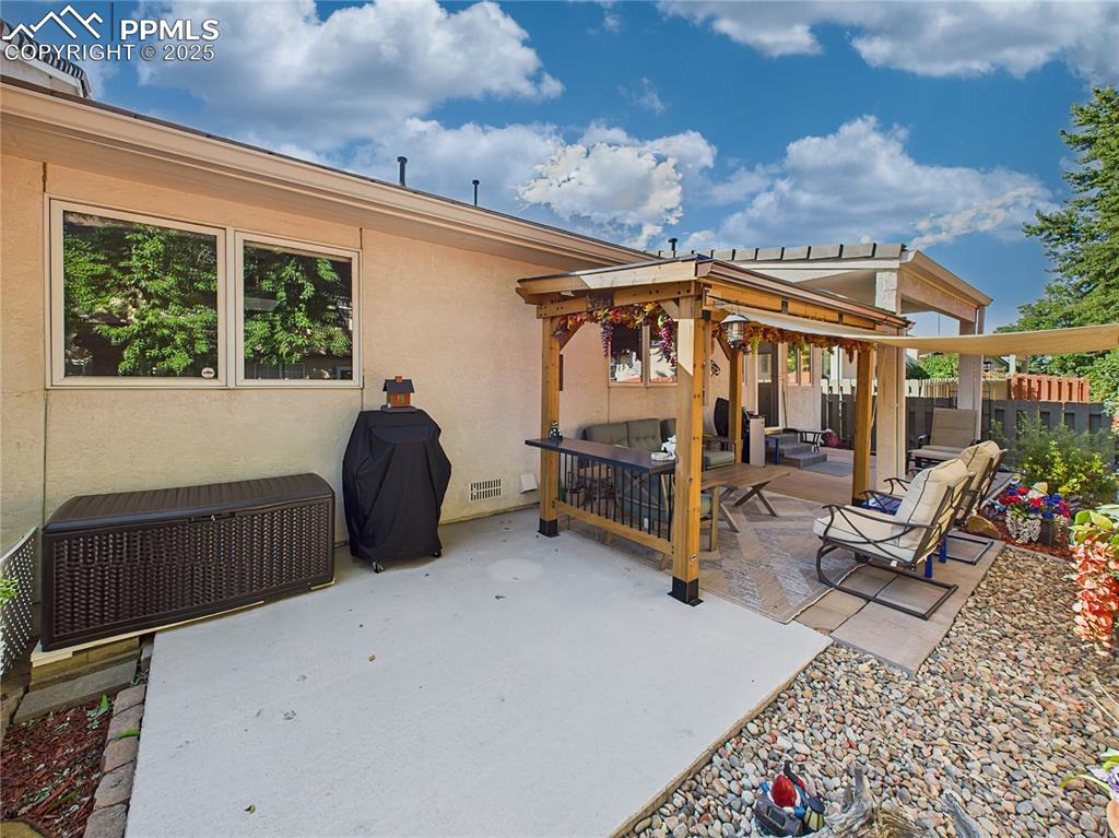 Pergola Seating Area – A beautifully crafted pergola and sun shade anchors the backyard, surrounded by a mix of stone landscaping and flower beds.