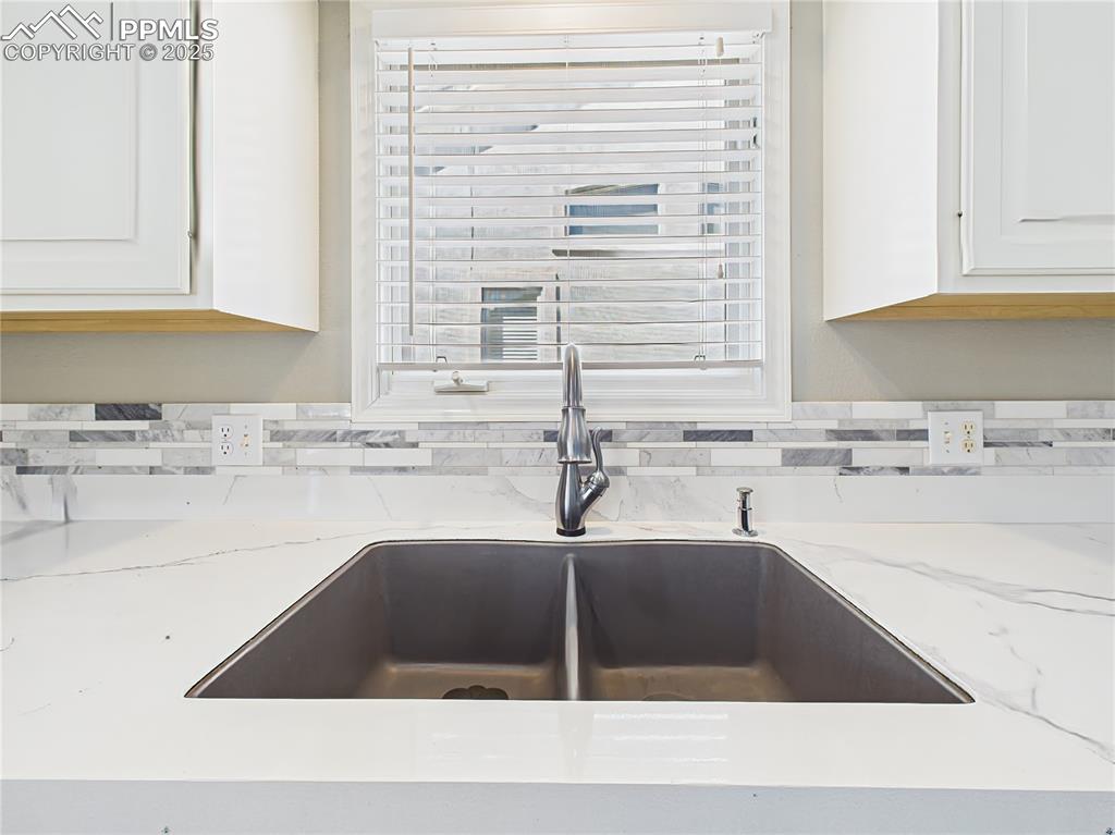 Kitchen Sink Detail – Matte black dual-basin sink with gooseneck faucet, accented by elegant marble-look counters and tiled backsplash.