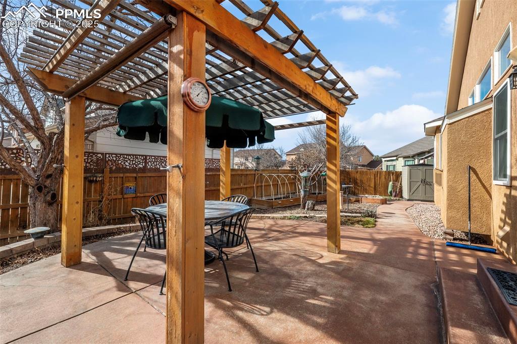 Fenced backyard with outdoor dining space, a pergola, a patio area, and a storage shed
