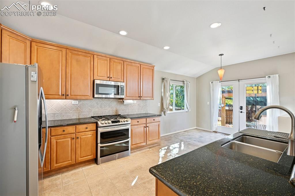 Kitchen featuring stainless steel appliances, gas range, dark stone counters, recessed lighting, and tasteful backsplash