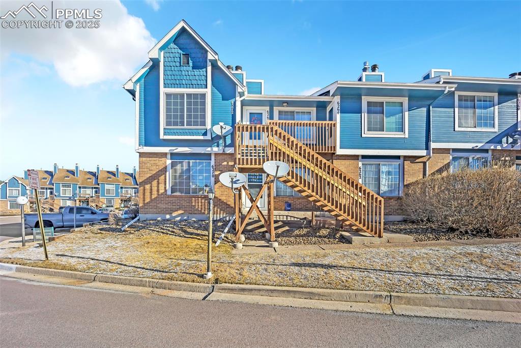 View of front facade with stairway, brick siding, and a residential view
