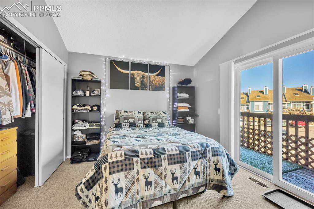Bedroom featuring light colored carpet, access to exterior, vaulted ceiling, and a closet