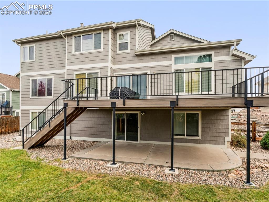 Back of house featuring stairway, a patio, a yard, and a deck