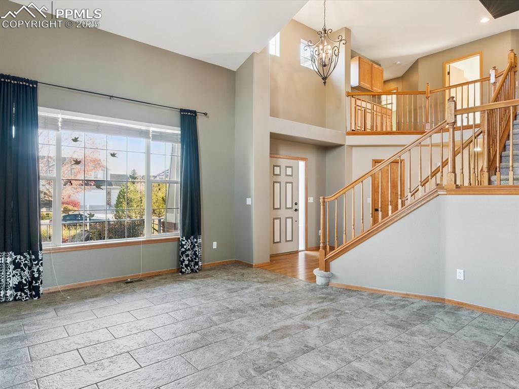 Foyer entrance featuring stairway, a chandelier, and a towering ceiling