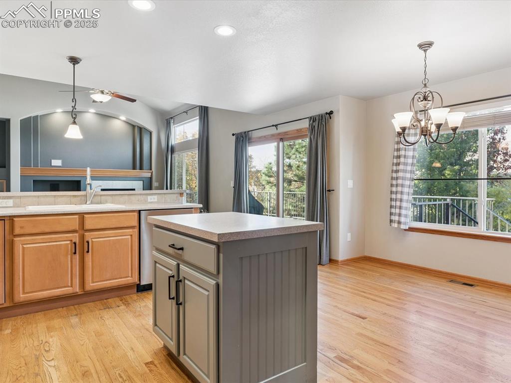Kitchen featuring decorative light fixtures, light countertops, light wood-type flooring, a center island, and recessed lighting