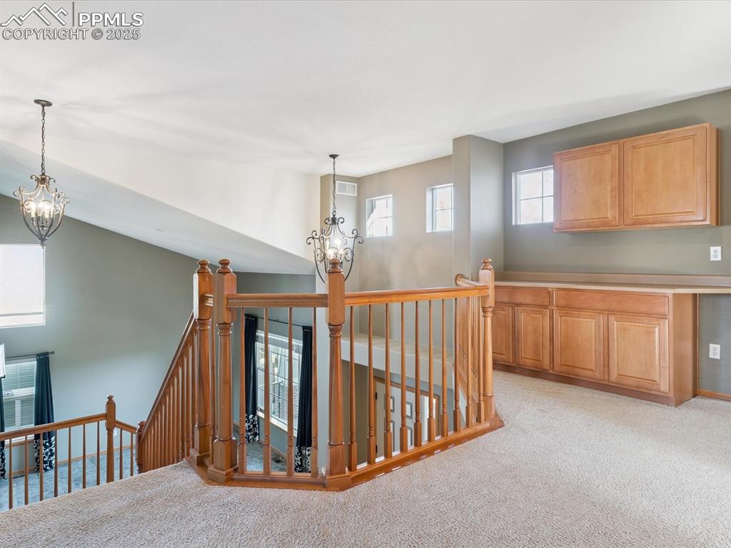 Hallway with a chandelier, an upstairs landing, and light carpet