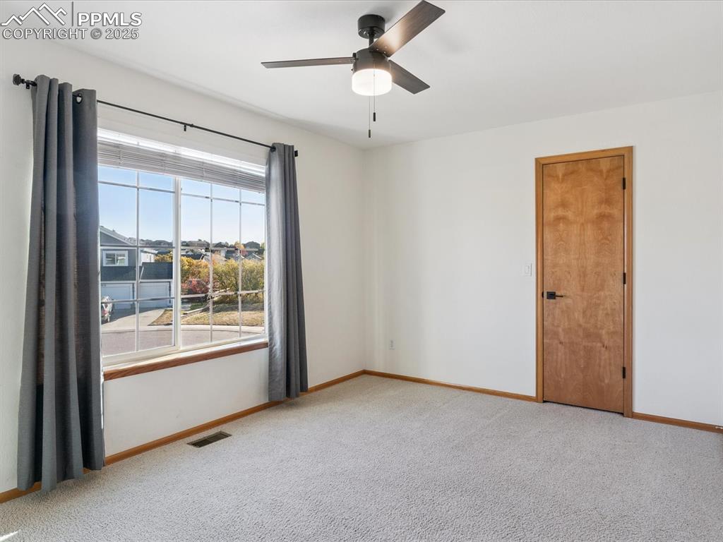 Empty room with light colored carpet and a ceiling fan