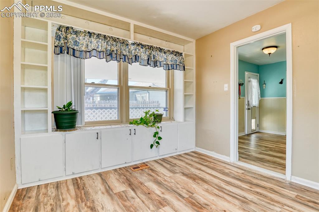 Unfurnished dining area with visible vents, built in shelves, light wood-style floors, and baseboards