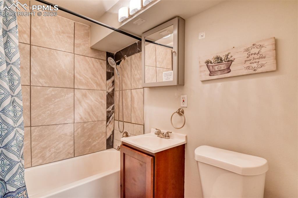 Full bath featuring toilet, vanity, and shower / tub combo with curtain