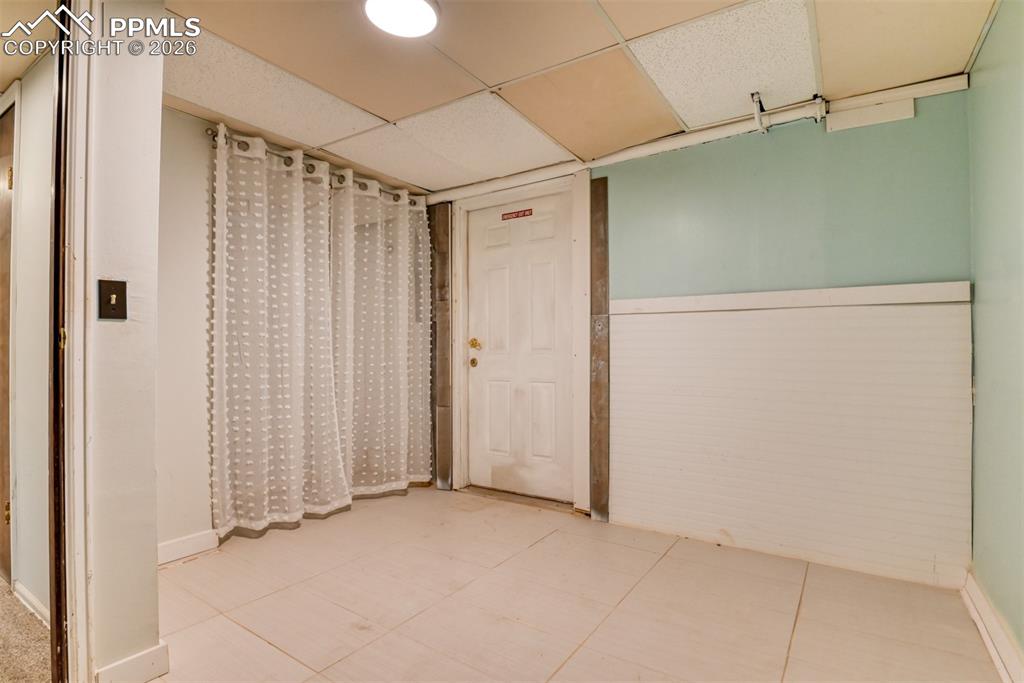 Unfurnished room with a paneled ceiling and light tile patterned flooring