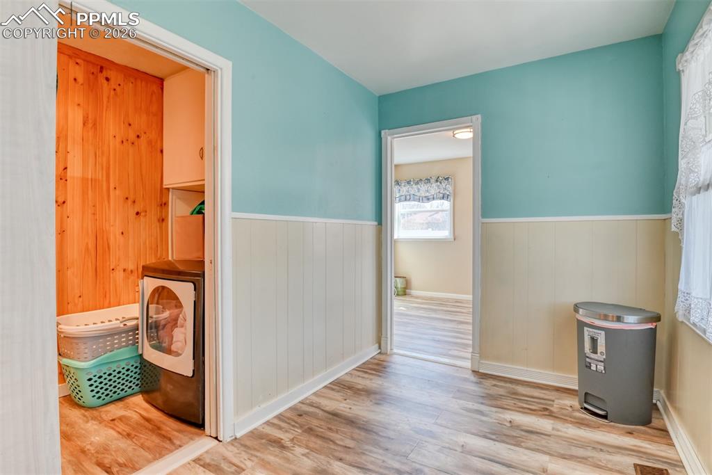 Hall featuring washer / dryer, a wainscoted wall, and wood finished floors