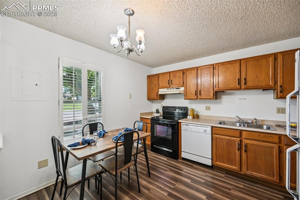 Kitchen with white appliances, decorative light fixtures, brown cabinets, light countertops, and a textured ceiling