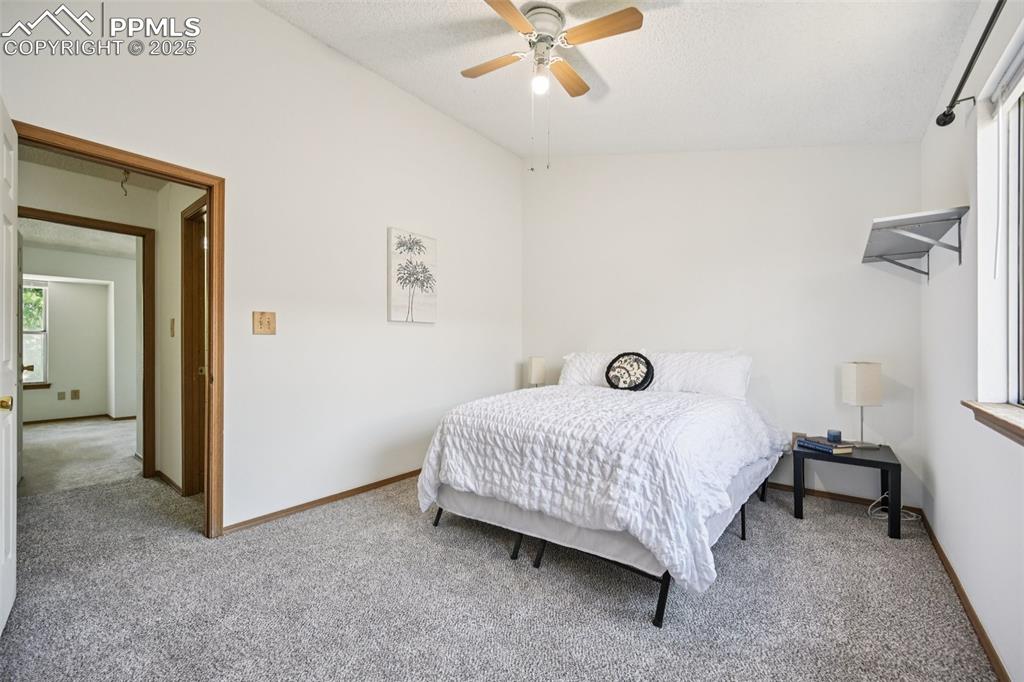 Carpeted bedroom featuring ceiling fan and a textured ceiling