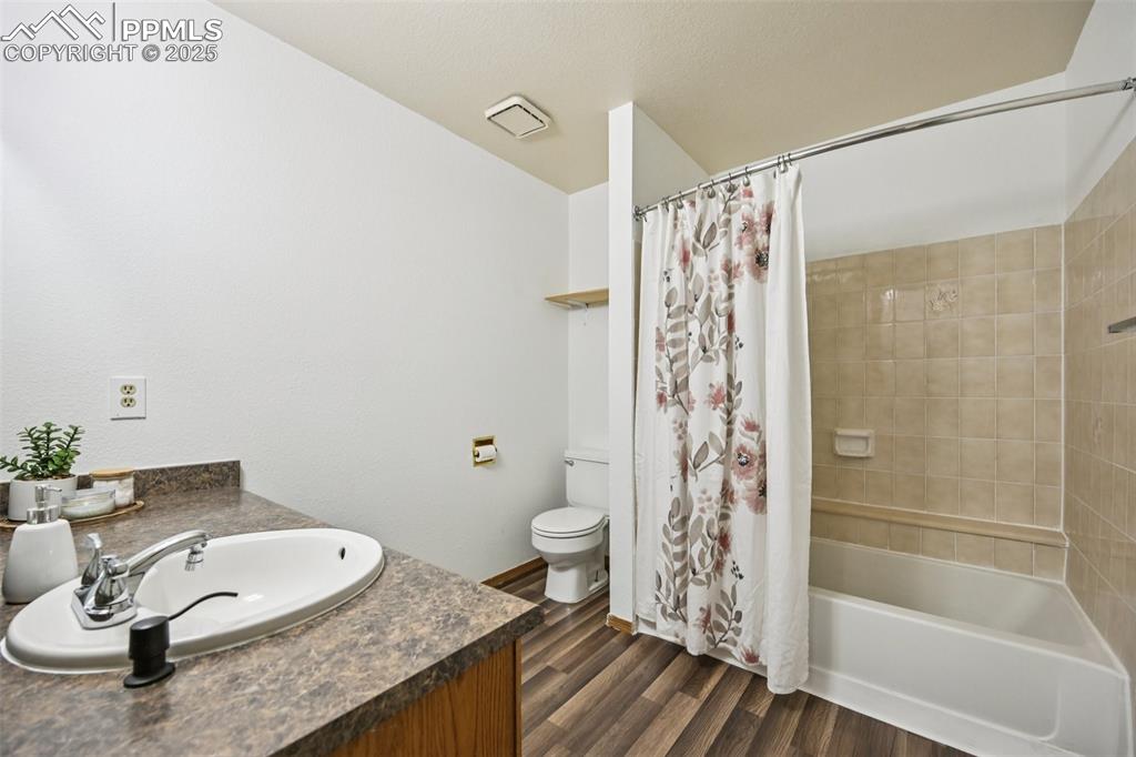 Full bathroom featuring shower / tub combo, dark wood-style floors, and vanity