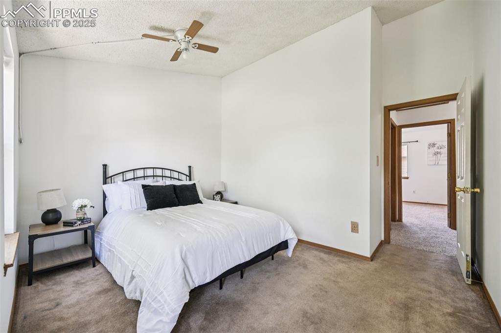 Bedroom with carpet floors, ceiling fan, and a textured ceiling