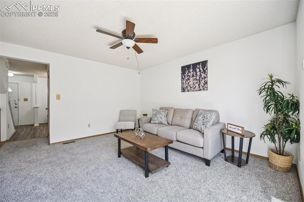 Living area with carpet floors, a textured ceiling, and ceiling fan
