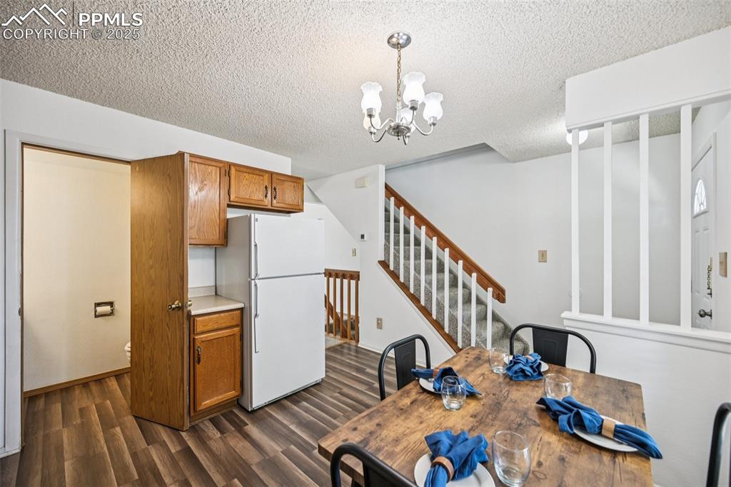 Unfurnished dining area with dark wood finished floors, a chandelier, a textured ceiling, and stairway