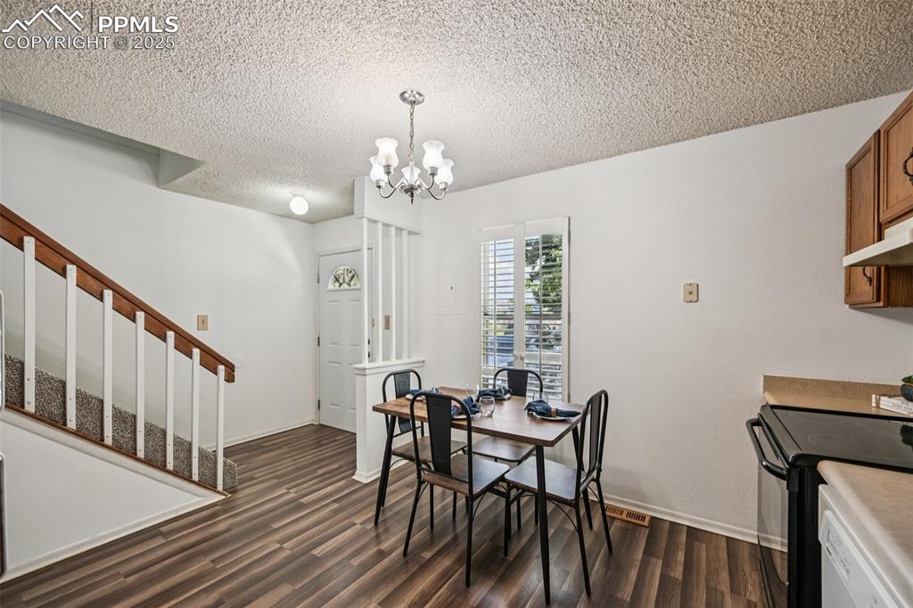 Dining area with a textured ceiling, a chandelier, dark wood-type flooring, and stairway