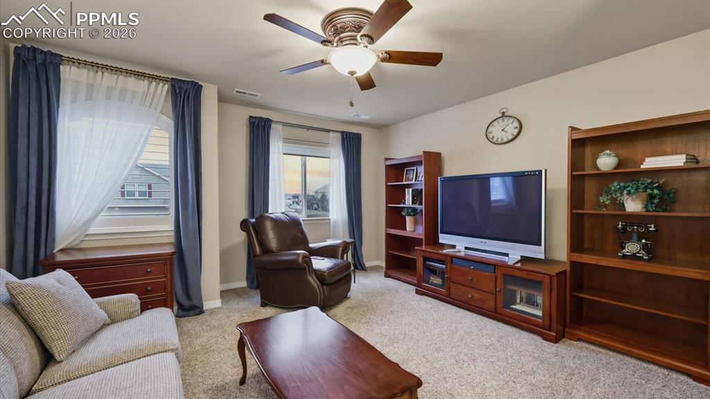 Light and bright upstairs Living Area with neutral carpet, a lighted ceiling fan, and lots of natural sunlight from the windows.
