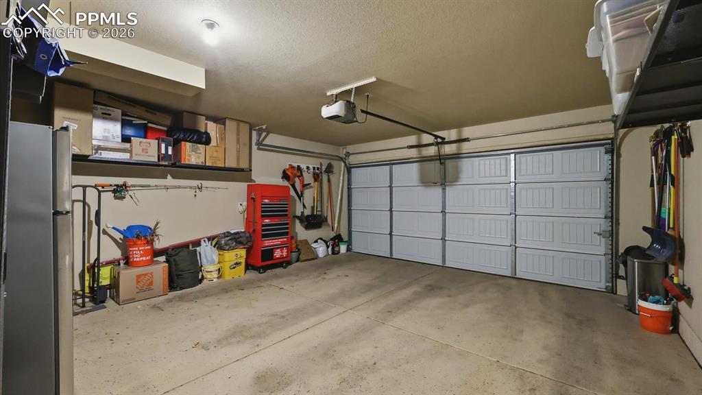 Two car attached garage with door opener and attached black storage racks that stay.