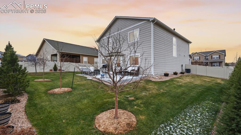 Nicely landscaped yard with a variety of trees, lush grass, and concrete patio for outdoor relaxation and fun.