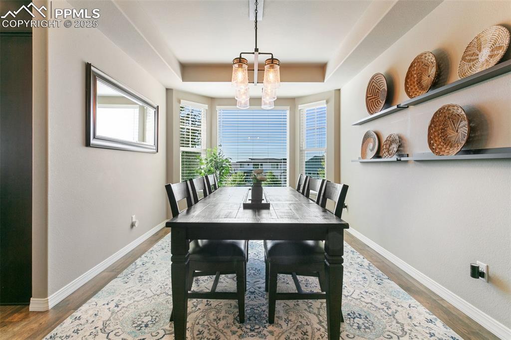 Dining room featuring light wood-style floors, a tray ceiling, and a chandelier