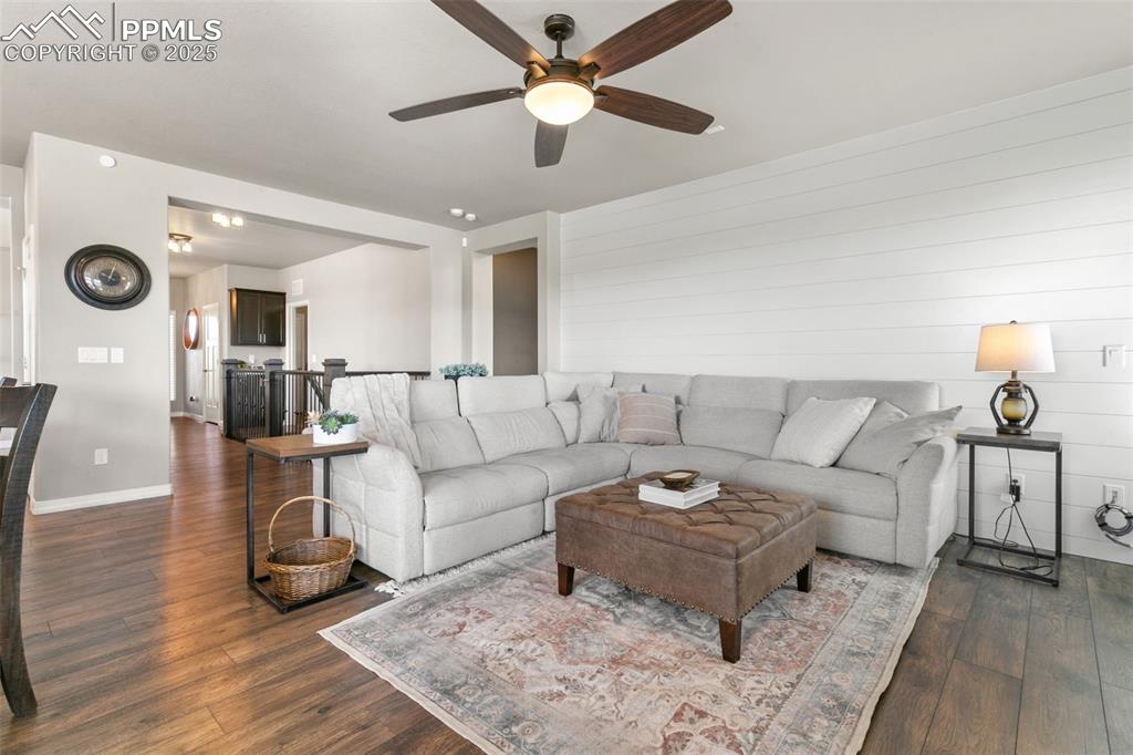 Living room with dark wood-type flooring and ceiling fan