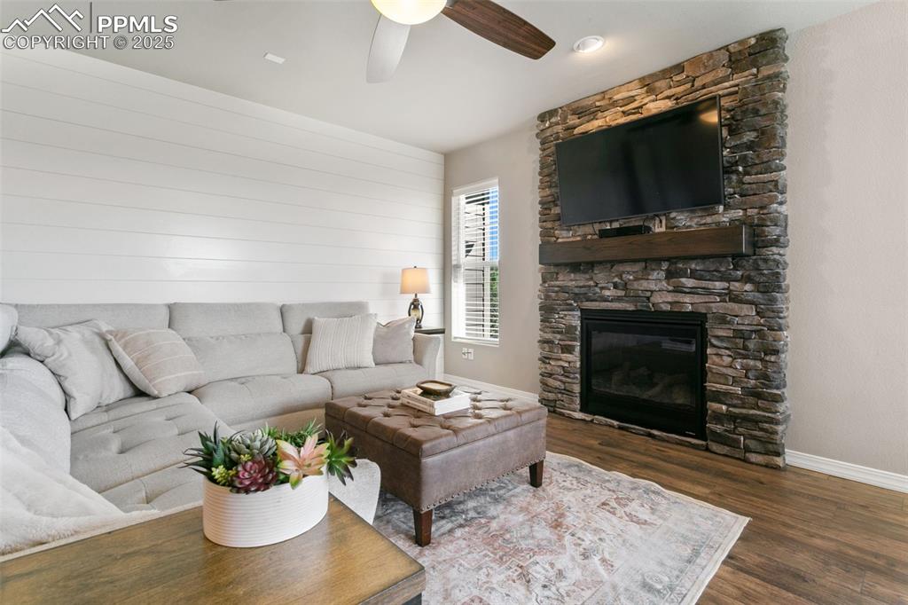 Living area featuring dark wood-type flooring, a fireplace, and a ceiling fan