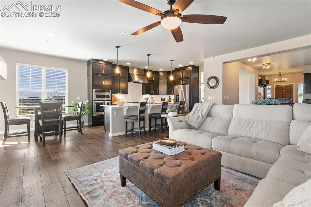 Living area with a chandelier, ceiling fan, dark wood-type flooring, and recessed lighting