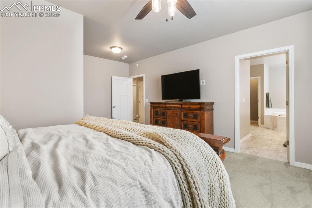 Carpeted bedroom featuring a ceiling fan, ensuite bathroom, and tile patterned floors