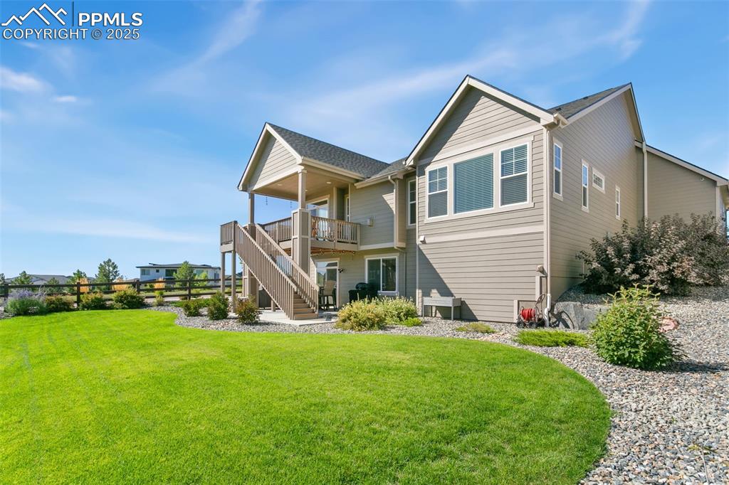 Rear view of property featuring stairway, a lawn, a wooden deck, and a patio area