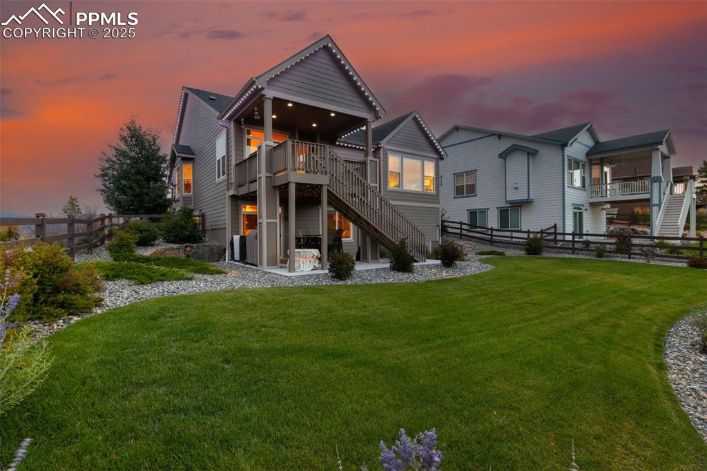 Back of property at dusk featuring stairs, a patio area, and a wooden deck