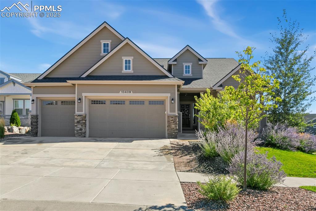 Craftsman house featuring a shingled roof, concrete driveway, and stone siding