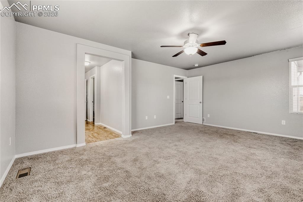 Master bedroom with windows, carpet, ceiling fan, and ensuite bathroom