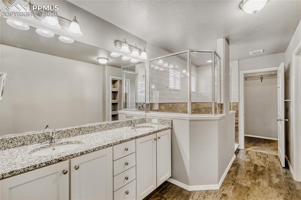 Master bathroom featuring a spacious closet, double vanity, tile floors, walk-in shower, and toilet closet 