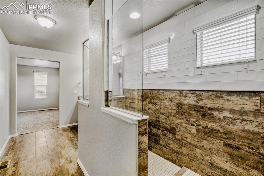 Master bathroom featuring a spacious closet, double vanity, tile floors, walk-in shower, and toilet closet