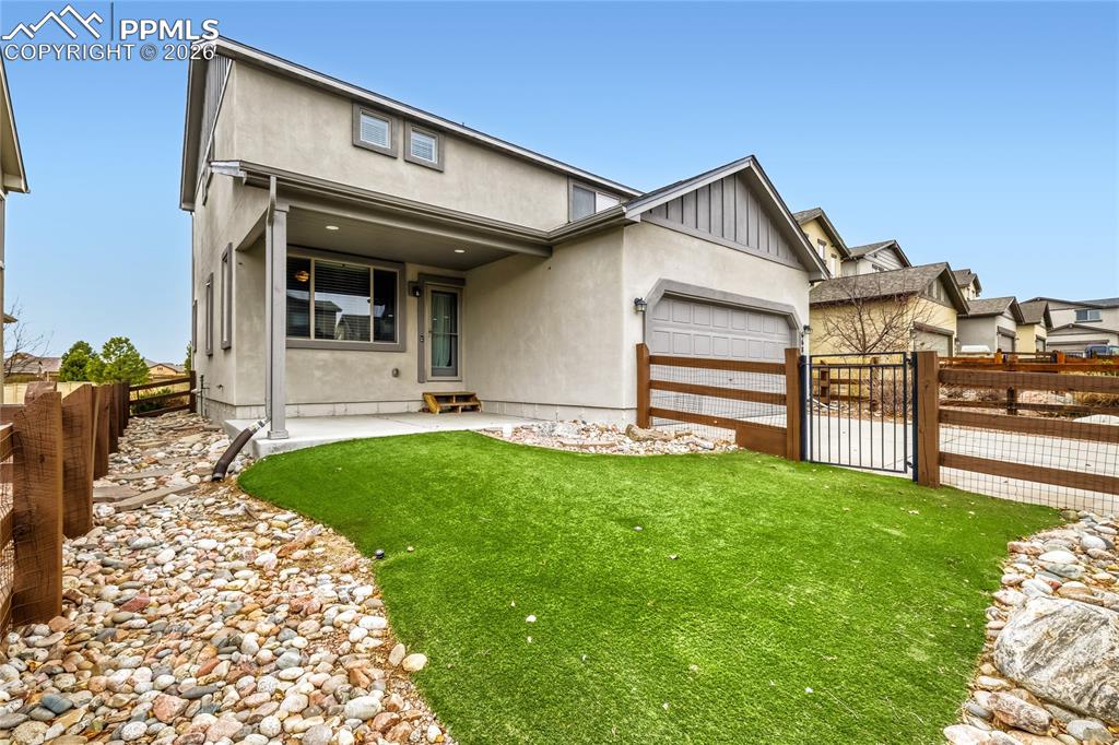 View of back of house featuring a gate, a patio area, and attached garage