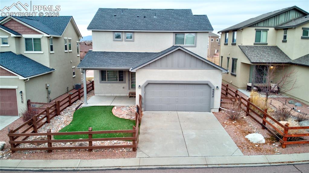 View of front of home with  shingled roof concrete driveway, a garage, a residential view, and stucco siding