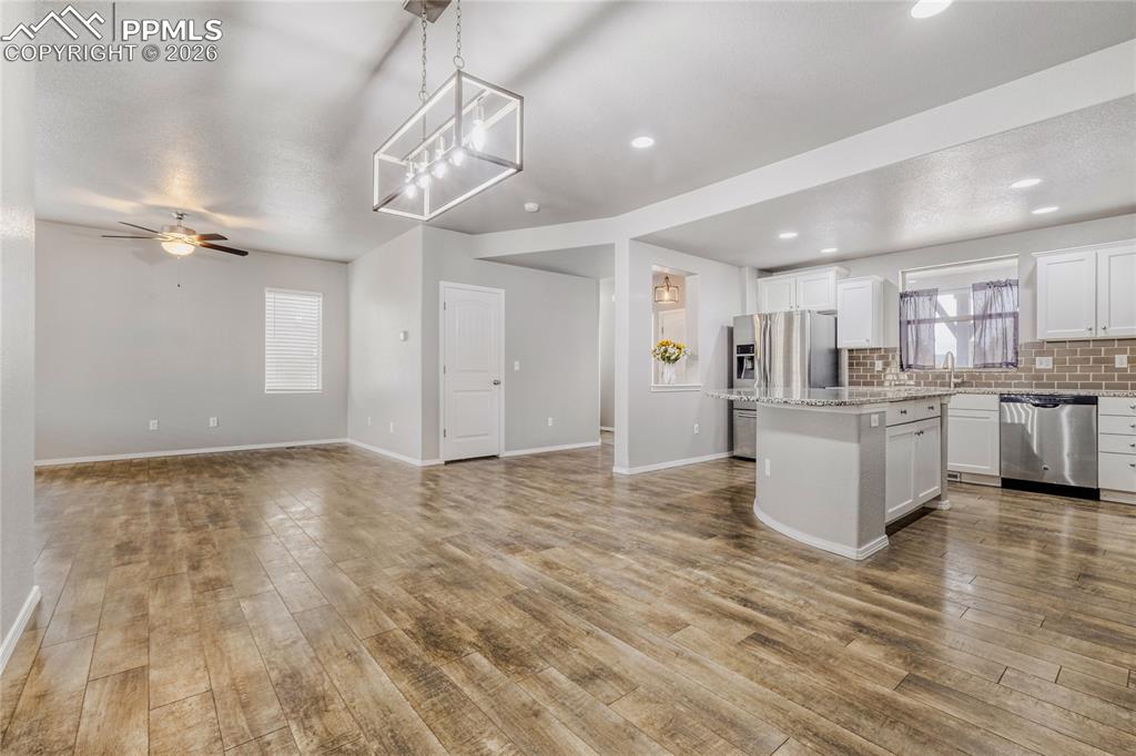 Kitchen with a center island, decorative light fixture, open floor plan, and backsplash