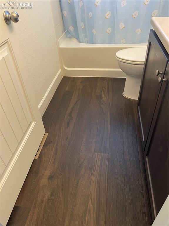 Full bath with vanity, shower / bath combo, and dark wood-style flooring