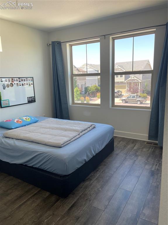 Bedroom featuring dark wood-style floors and baseboards