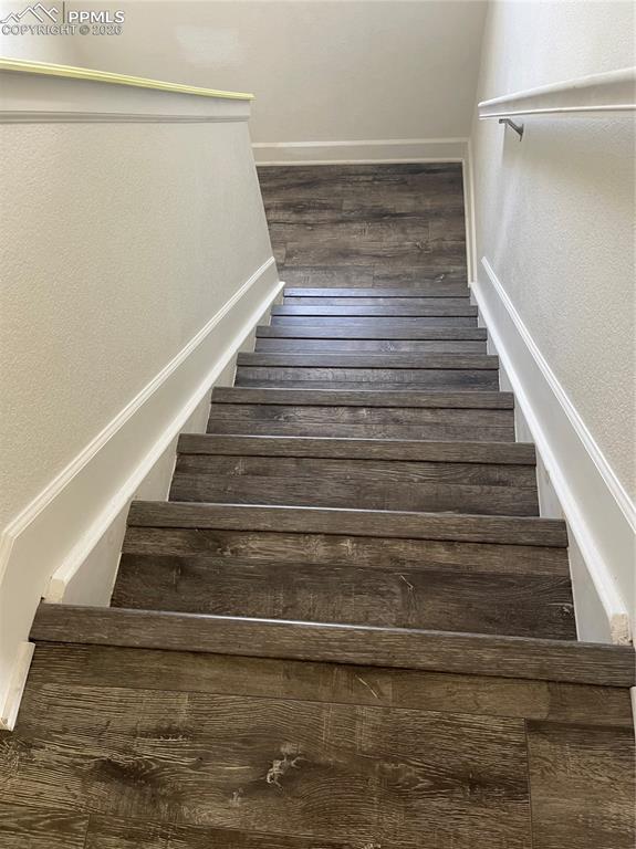 Stairs featuring a textured wall and wood finished floors
