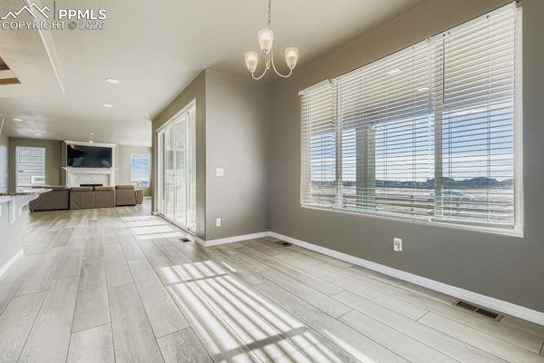 Unfurnished dining area with light wood-style flooring, a chandelier, and a fireplace