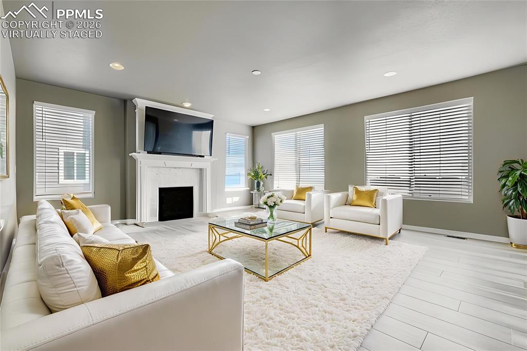 Virtually staged main level living room featuring a fireplace, light wood-style flooring, and recessed lighting