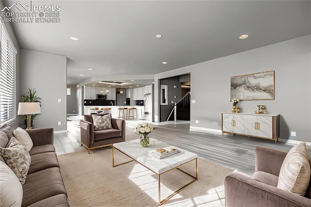 Virtually staged main level living room featuring a fireplace, light wood-style flooring, and recessed lighting