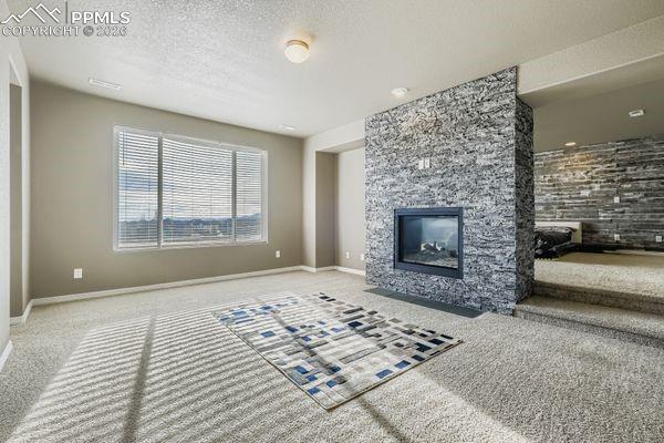 Unfurnished living room with a fireplace, carpet, and a textured ceiling